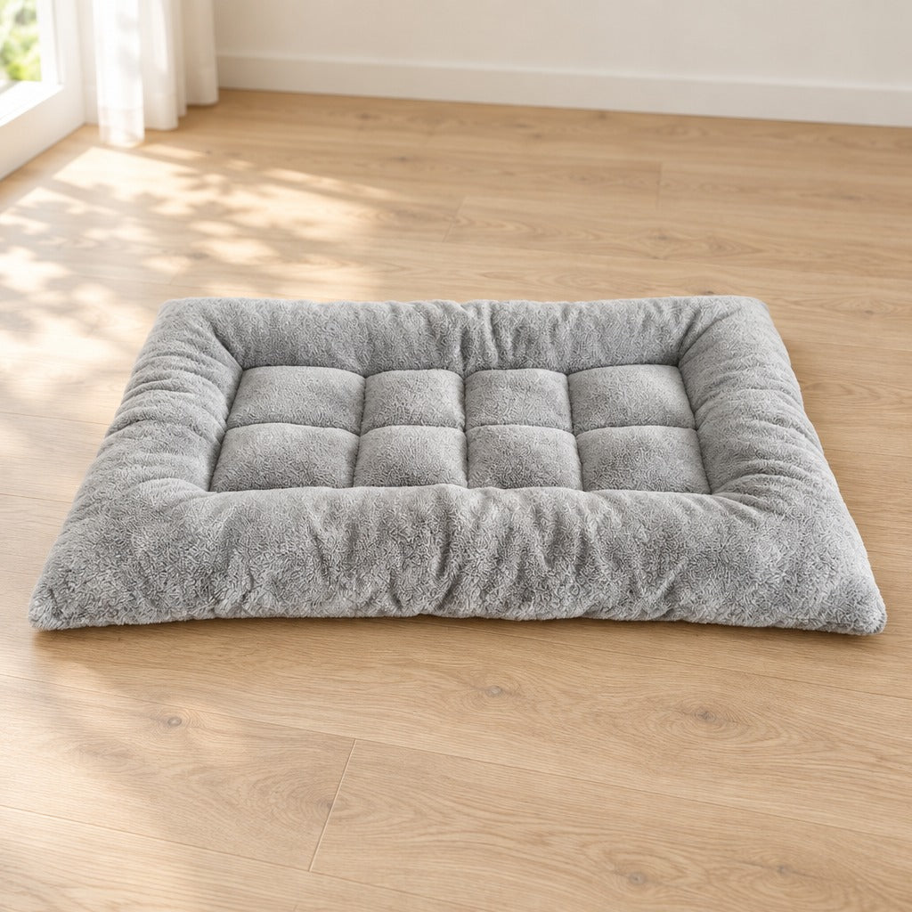Tapis matelassé gris perle posé seul à plat sur un parquet clair, vu de trois quarts.